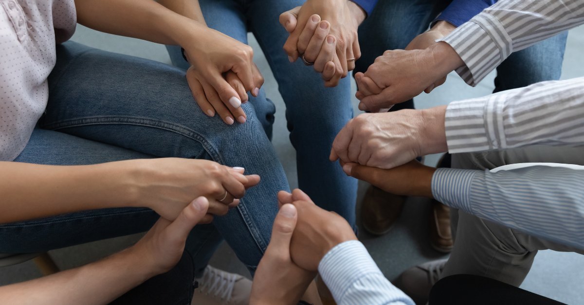 People holding hands in a supportive circle, symbolizing the multiple pathways approach to addiction recovery.