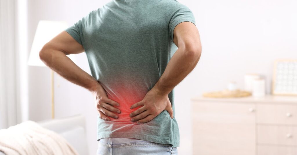 Man holding his lower back in pain, symbolizing the connection between addiction and injuries.