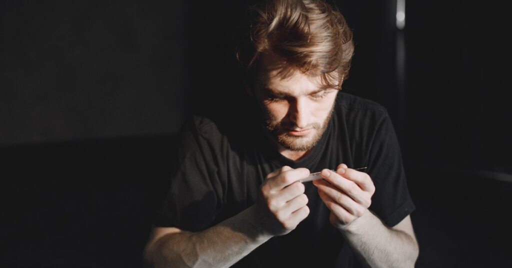 A man intensely focusing on an object in his hands, representing the connection between addiction and autism.